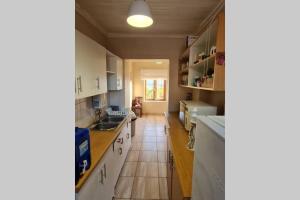 a kitchen with white cabinets and a tile floor at Cosy stone cottage in Stilbaai