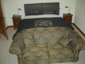 a bedroom with a bed with a couch in front of it at Alltyfyrddin Farm Guest House at The Merlin's Hill Centre in Carmarthen