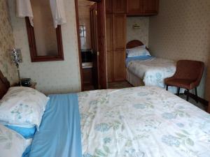 niewielka sypialnia z 2 łóżkami i krzesłem w obiekcie Alltyfyrddin Farm Guest House at The Merlin's Hill Centre w mieście Carmarthen