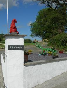 une statue d'un chien assis au-dessus d'un mur dans l'établissement Alltyfyrddin Farm Guest House at The Merlin's Hill Centre, à Carmarthen