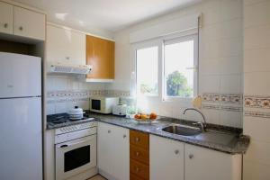 cocina con fregadero y nevera blanca en Residencial L'Hort, en Denia