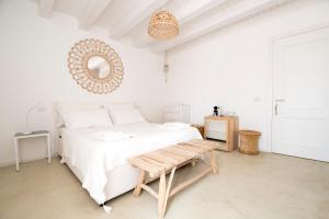 a white bedroom with a large bed and a table at Casa Memi in Marzamemi