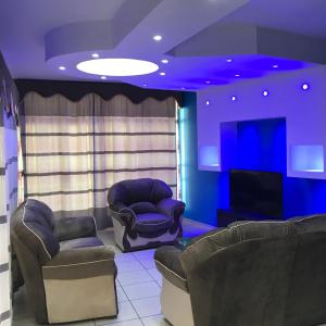 uma sala de estar com duas cadeiras e uma televisão em Damara Gardens em Windhoek
