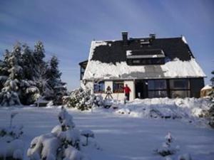 ein schneebedecktes Gebäude mit einer Person, die davor steht in der Unterkunft Ferienwohnung Haus Sonnenhügel in Kurort Altenberg