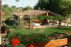 a small house with a yard with flowers and a backyard at Podere La Vecchia Fornace in Cortona