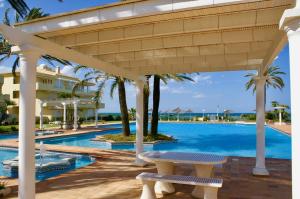 - une piscine avec une pergola et une table de pique-nique à côté d'un complexe dans l'établissement Playa Dorada, à Dénia