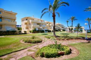 un complexe avec des palmiers et un bâtiment dans l'établissement Playa Dorada, à Dénia