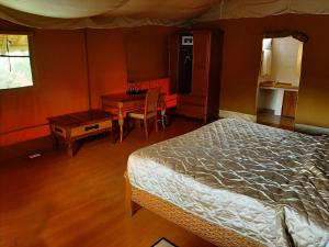 um quarto com uma cama, uma secretária e uma mesa em AA Lodge Amboseli em Amboseli