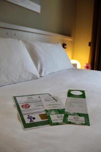 dos folletos sobre una cama blanca en Green Class Hotel Candiolo, en Candiolo