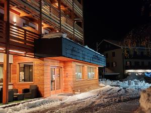 ein Holzgebäude im Schnee in der Nacht in der Unterkunft Edelweiss Alpine Nature in Pinzolo