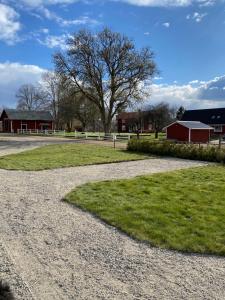 a gravel road in front of a red barn at Hults-Boaryd Golf och B&B in Hult