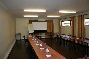una sala conferenze con un lungo tavolo con sedie e uno schermo di Europrime Hotel a Boksburg