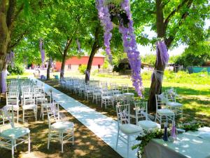 Un pasillo de bodas con sillas blancas y flores púrpuras en Agriturismo Corte dei Landi en Cadè