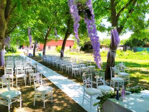 Un pasillo de bodas con sillas blancas y flores púrpuras en Agriturismo Corte dei Landi, en Cadè