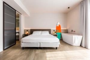 a white bedroom with a bed and a bathtub at GoTì Hotel in Nago-Torbole