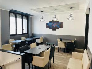 una sala da pranzo con tavoli, sedie e luci di Hotel Perugino a Milano