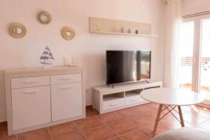 uma sala de estar com uma televisão e uma mesa em Apartamento nuevo junto a la playa vistas al mar em Punta Umbría