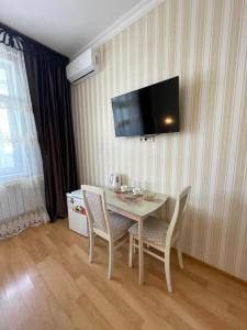 a dining room table with chairs and a television on a wall at Mini-Hotel Sultan in Astana