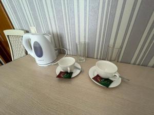 a table with two cups and a coffee maker at Mini-Hotel Sultan in Astana