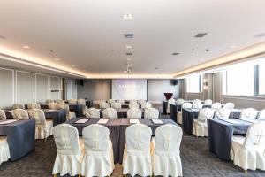 una sala conferenze con tavoli, sedie e uno schermo di Mercure Xian City Centre a Xi'an