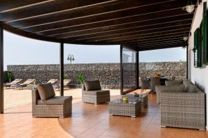 een patio met stoelen en tafels en een stenen muur bij Villa Adelina in Punta de Mujeres