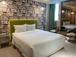 a bedroom with a white bed and a wall of books at 浪琴Motel文創旅館 in Taichung