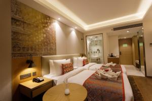 a hotel room with a white bed and a table at Sayaji Jamnagar in Jamnagar