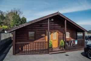 Cabaña de madera pequeña con porche y puerta en Donard Shadow Lodge, en Newcastle