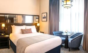 a hotel room with a bed and a chair at The Grand Hotel Birmingham in Birmingham