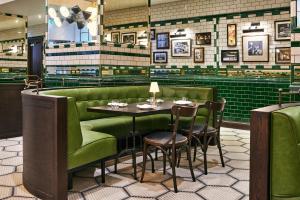 a restaurant with green booths and a table and chairs at The Grand Hotel Birmingham in Birmingham