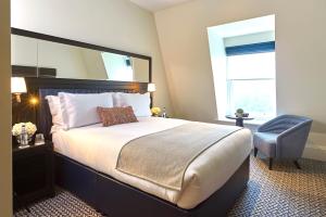 a bedroom with a large bed and a chair at The Grand Hotel Birmingham in Birmingham