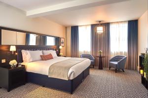 a hotel room with a bed and a chair at The Grand Hotel Birmingham in Birmingham
