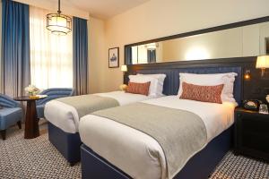a hotel room with two beds and a chair at The Grand Hotel Birmingham in Birmingham