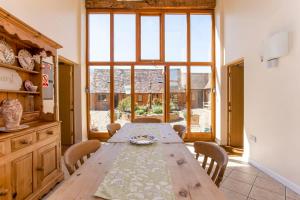 een eetkamer met een houten tafel en een groot raam bij Bridge Farm Holiday Cottages in Cow Honeybourne