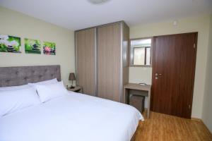 1 dormitorio con cama blanca y armario de madera en Feel at Home en Sandanski