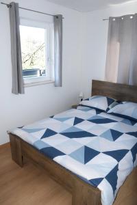 uma cama azul e branca num quarto com uma janela em M&M Apartment em Zgornje Gorje