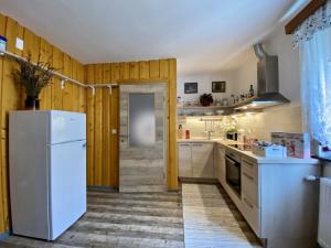 a kitchen with a white refrigerator and wooden walls at Apartment Ravnik in Bled