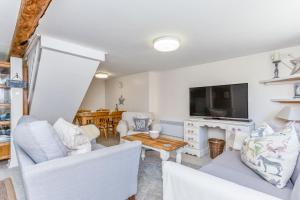 a living room with white furniture and a flat screen tv at Bridge Farm Holiday Cottages in Cow Honeybourne