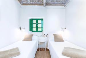 2 camas en una habitación blanca con mesa en Terra Ecoturismo Casa La Casita verde, en La Focella