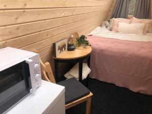 a room with two beds and a table with a microwave at Niiralan Tila : Starlite Cabin in Laitila