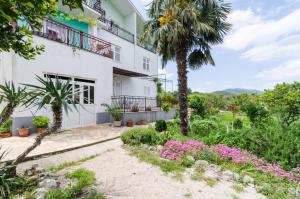 a white building with palm trees and flowers at Apartments Sutvid in Drače