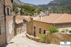 eine Gasse in einer Stadt mit Häusern und Bergen in der Unterkunft YourHouse Es Niu, apartment in Puerto de Sóller in Sóller