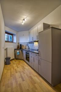 a kitchen with a white refrigerator and wooden floors at Ferienwohnung Amelie in Wenzenbach