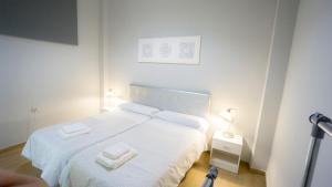 a white bedroom with a bed with two towels on it at Deluxe Apartment in La Giralda in Seville