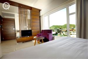 - une chambre avec un lit, une télévision et une chaise dans l'établissement Hotel Daani Continental, à Imphal