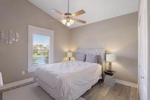 a bedroom with a white bed and a ceiling fan at Stunning home with pool, dock and direct gulf access in Marco Island +22 photos