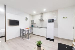 eine Küche mit weißen Schränken und einem Tisch im Zimmer in der Unterkunft Moonkey - Apartamento Amaralba B in Alicante