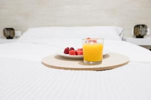 einen Obstteller und ein Glas Orangensaft auf dem Bett in der Unterkunft Moonkey - Apartamento Amaralba B in Alicante