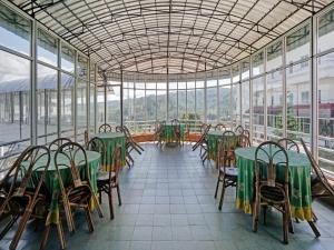 a restaurant with green tables and chairs and windows at OYO 90028 Hotel Victory in Batu