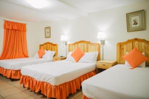 two beds in a hotel room with orange pillows at Hotel La Estacion in Granada